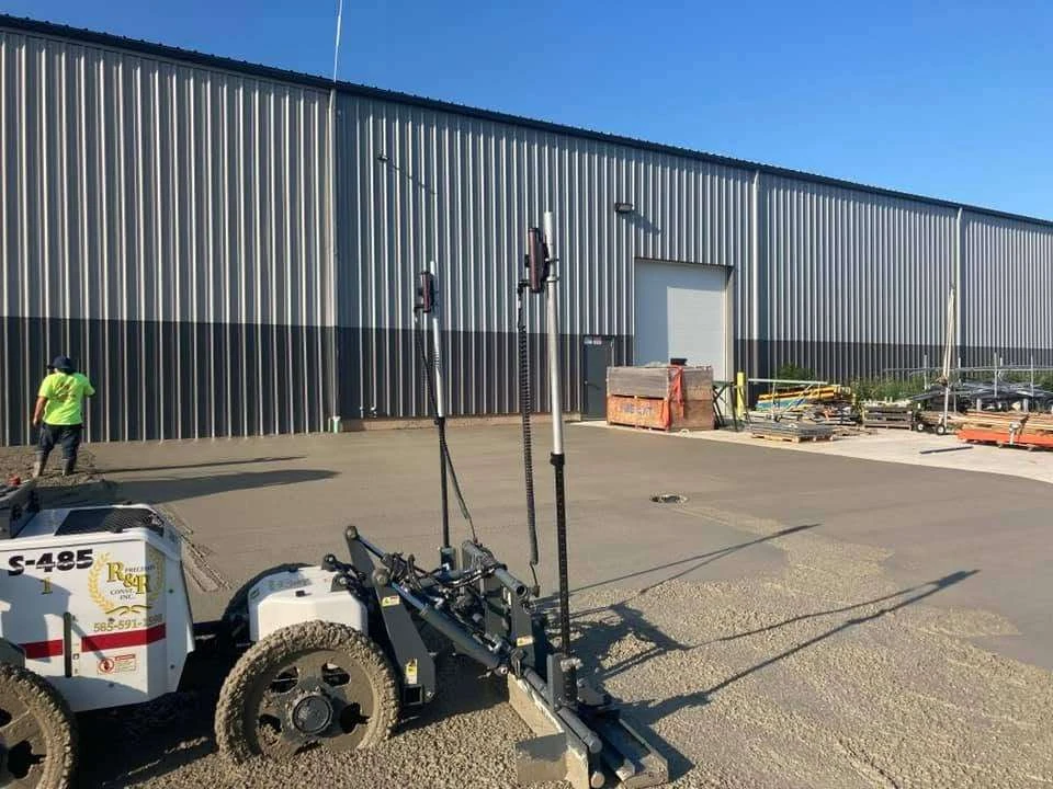 R&R laser screed equipment placing concrete alongside a commercial building